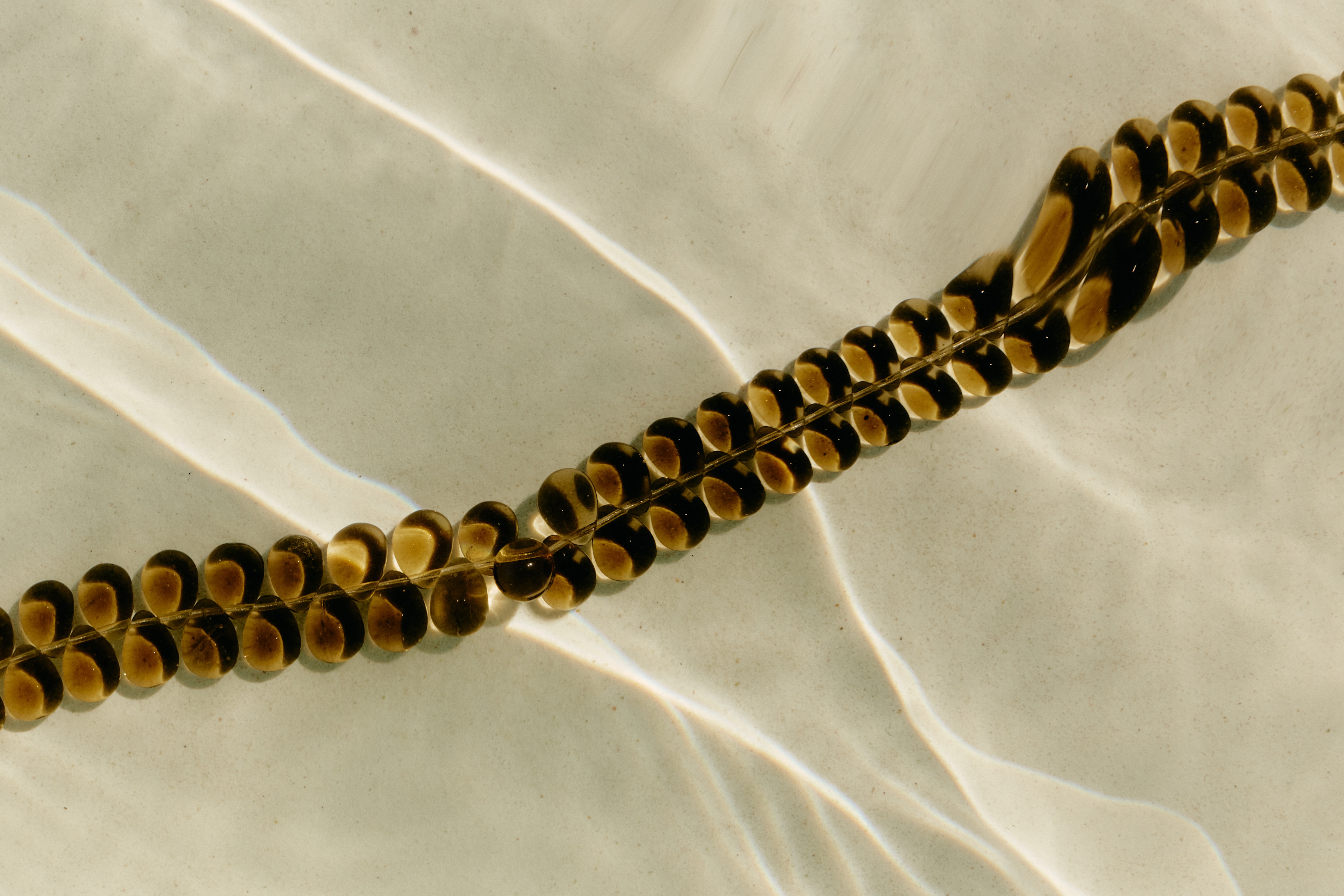 A short necklace made of round, warm tea-toned beads arranged in a layered, sculptural pattern. Comfortable to wear, it sits neatly on the neckline and works well with both casual and more dressed-up looks.

Glass beads 
Sterling silver hardware

44 cm length

Handcrafted in Berlin